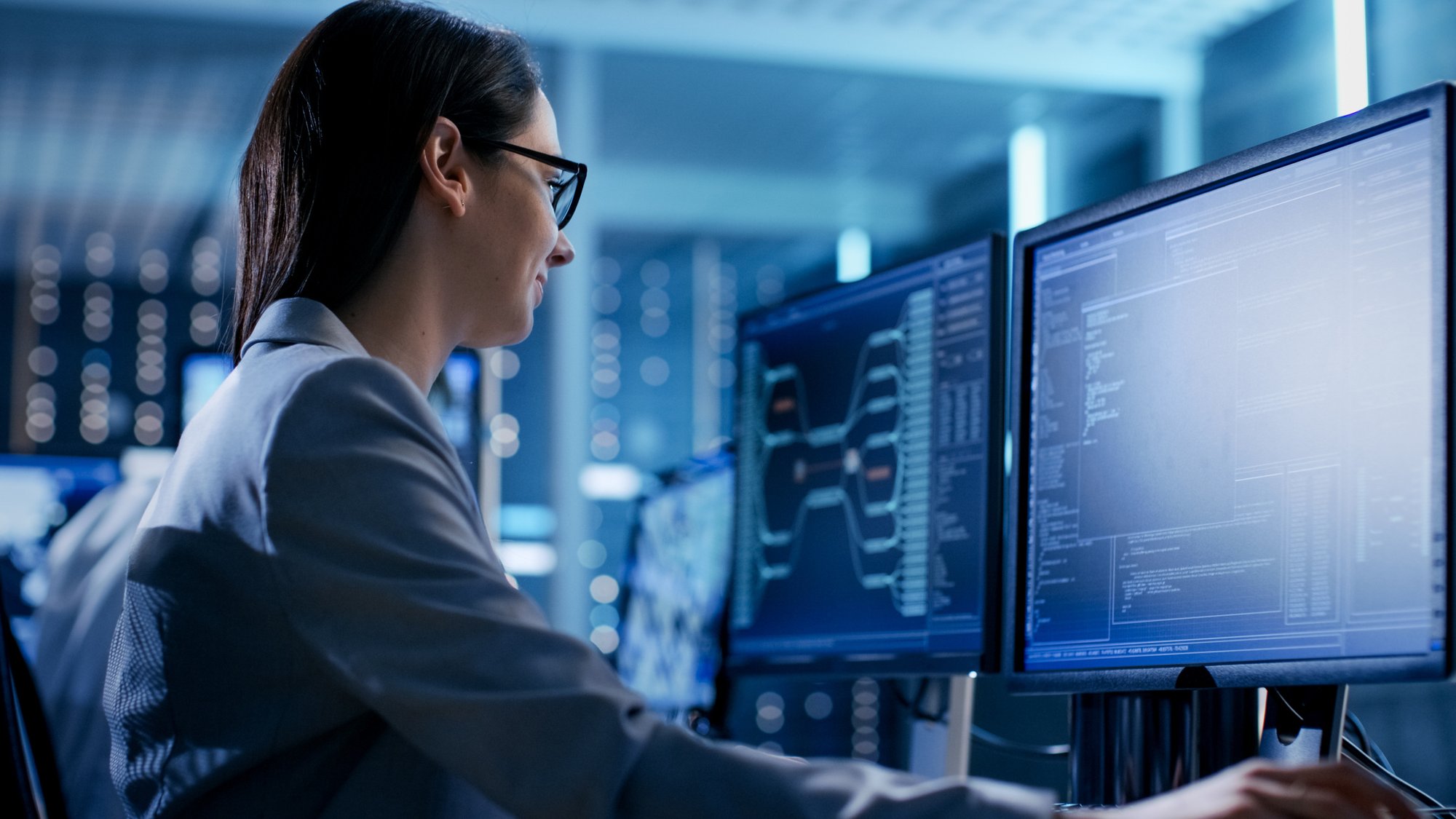 Close-up-Shot-of-Female-IT-Engineer-Working-in-Monitoring-Room.-She-Works-with-Multiple-Displays.-808157346_2313x1301