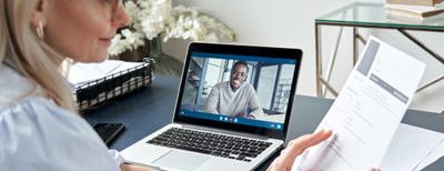 older woman interviewing young man over the computer