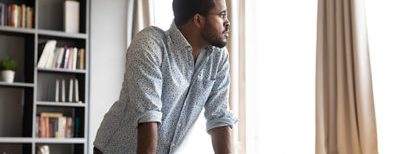 man standing over computer looking out the window