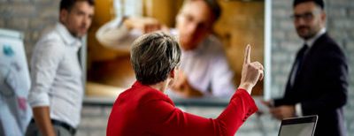 woman in red jacket holding up finger talking to two men